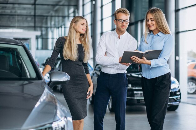 Familia joven eligiendo un automóvil en una sala de exposición de automóviles