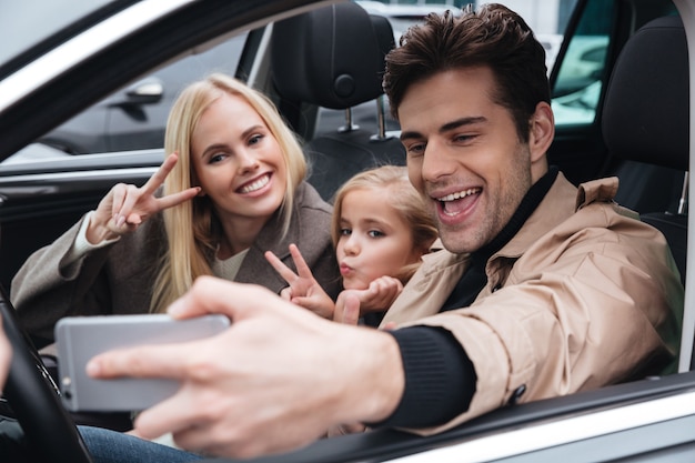 Familia joven feliz hacer selfie por teléfono móvil.