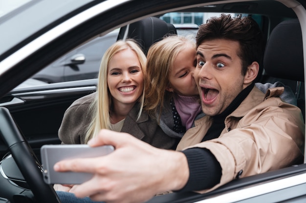 Familia joven feliz hacer selfie por teléfono móvil.