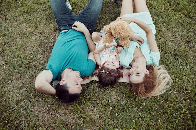 Familia joven feliz pasar tiempo juntos afuera en la naturaleza verde.