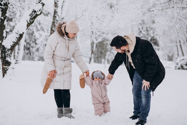 Familia joven con hija pequeña en un bosque de invierno lleno de nieve