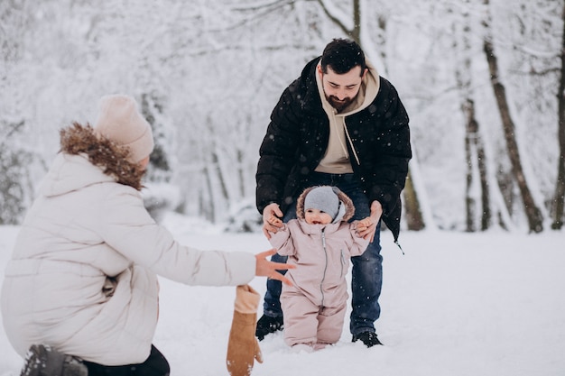 Familia joven con hija pequeña en un bosque de invierno lleno de nieve