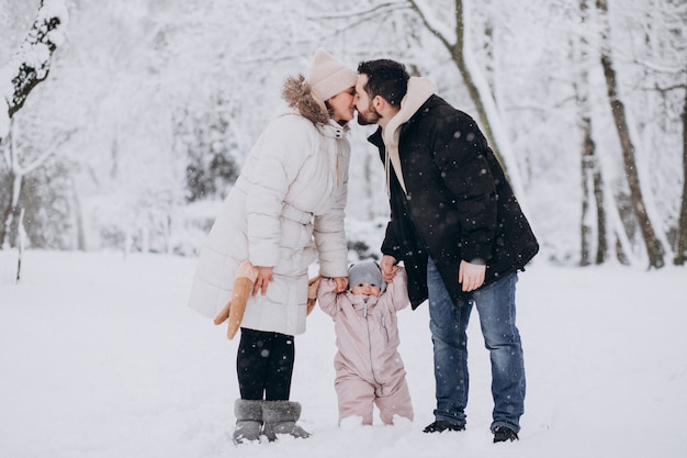 Familia joven con hija pequeña en un bosque de invierno lleno de nieve