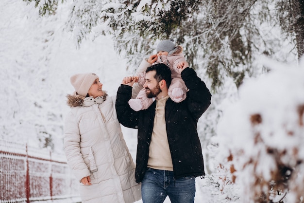 Familia joven con hija pequeña en un bosque de invierno lleno de nieve