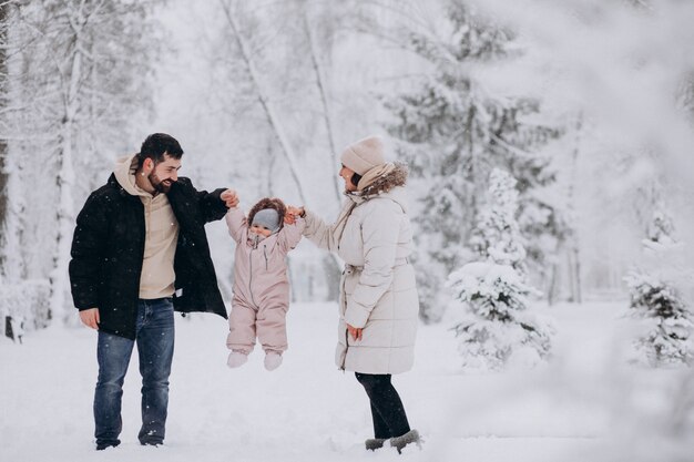 Familia joven con hija pequeña en un bosque de invierno lleno de nieve