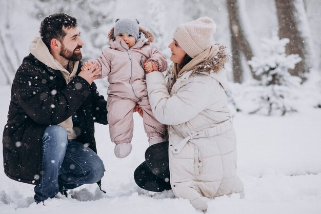 Familia joven con hija pequeña en un bosque de invierno lleno de nieve