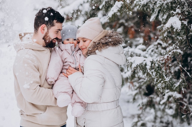 Familia joven con hija pequeña en un bosque de invierno lleno de nieve