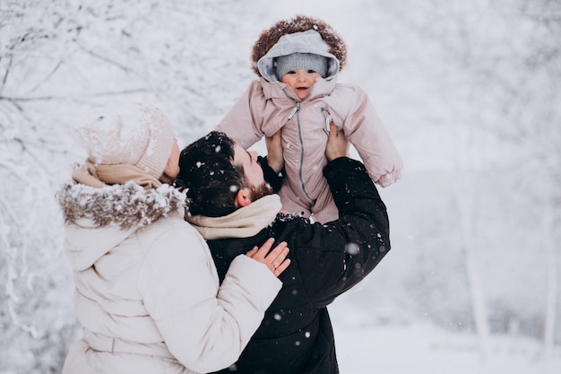 Familia joven con hija pequeña en un bosque de invierno lleno de nieve