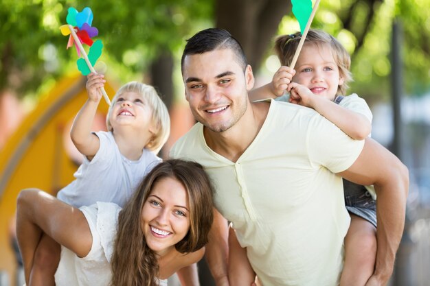 Familia joven jugando coloridos molinos de viento con niños