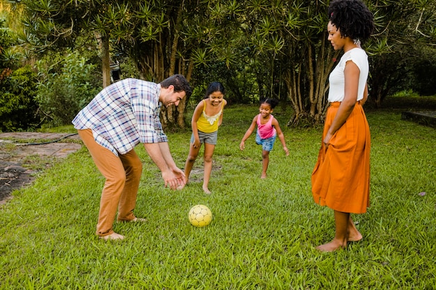 Familia joven jugando a la pelota en el jardin