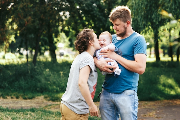 Familia joven, madre padre e hijo feliz posando en el parque