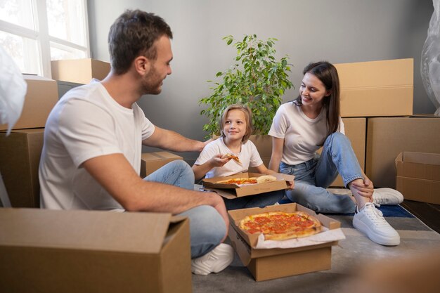 Familia joven mudándose a una nueva casa y comiendo pizza