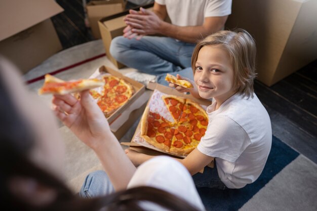 Familia joven mudándose a una nueva casa y comiendo pizza