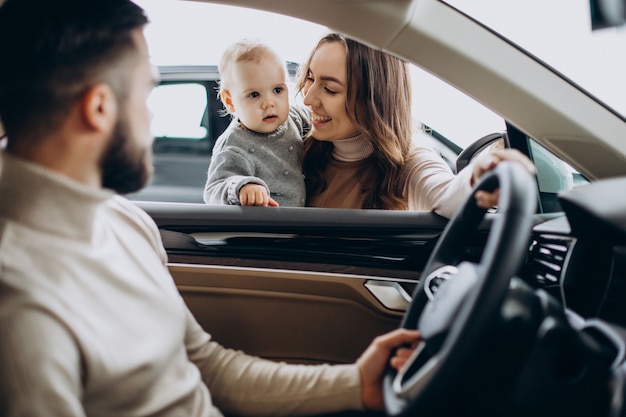 Familia joven con niña eligiendo un coche