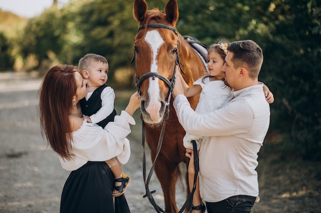 Familia joven con niños divirtiéndose con caballos en el bosque