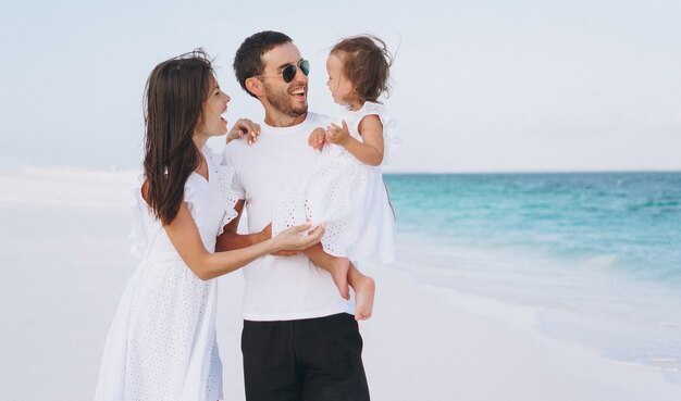 Familia joven con pequeña hija en vacaciones junto al mar