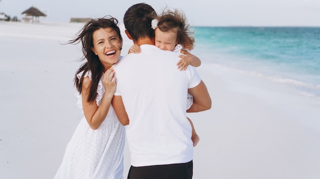 Familia joven con pequeña hija en vacaciones junto al mar