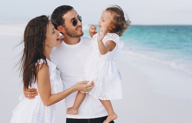 Foto gratuita familia joven con pequeña hija en vacaciones junto al mar