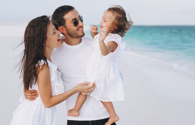 Familia joven con pequeña hija en vacaciones junto al mar