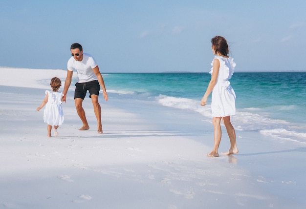 Familia joven con pequeña hija en vacaciones junto al mar