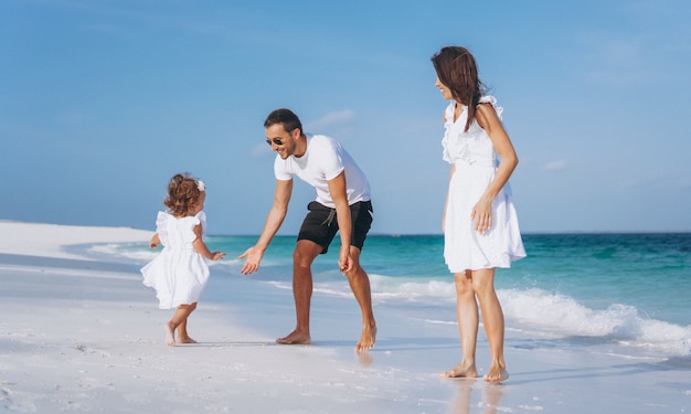 Familia joven con pequeña hija en vacaciones junto al mar