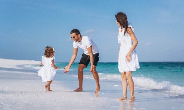 Familia joven con pequeña hija en vacaciones junto al mar