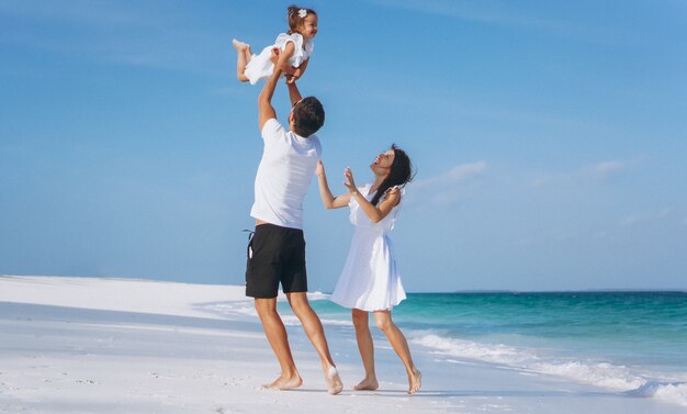 Familia joven con pequeña hija en vacaciones junto al mar