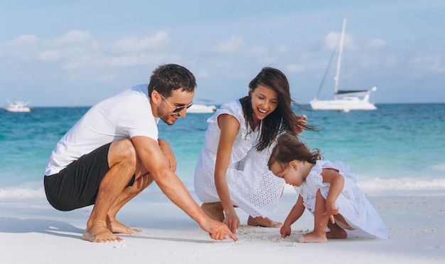 Familia joven con pequeña hija en vacaciones junto al mar