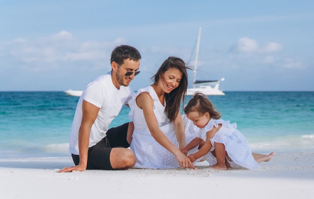 Familia joven con pequeña hija en vacaciones junto al mar