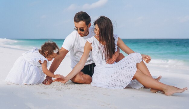 Familia joven con pequeña hija en vacaciones junto al mar