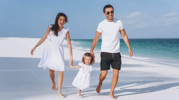 Familia joven con pequeña hija en vacaciones junto al mar