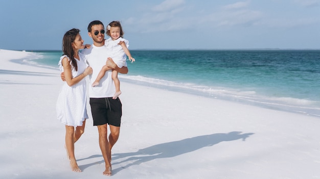 Familia joven con pequeña hija en vacaciones junto al mar