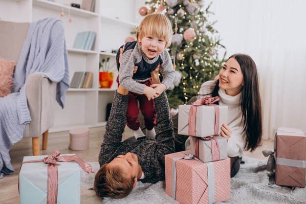 Familia joven con pequeño hijo por árbol de Navidad