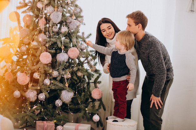 Familia joven con pequeño hijo decorar árbol de navidad