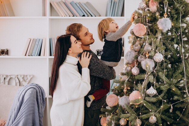 Familia joven con pequeño hijo decorar árbol de Navidad