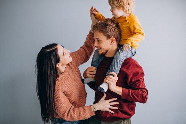 Familia joven con pequeño hijo juntos en gris