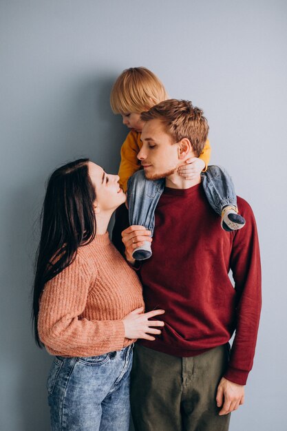 Familia joven con pequeño hijo juntos en gris