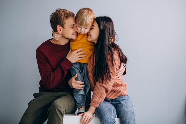 Familia joven con pequeño hijo juntos en gris