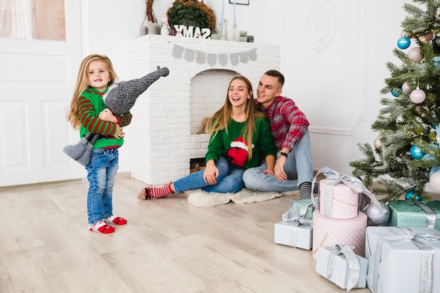 Familia joven en salón con árbol de navidad