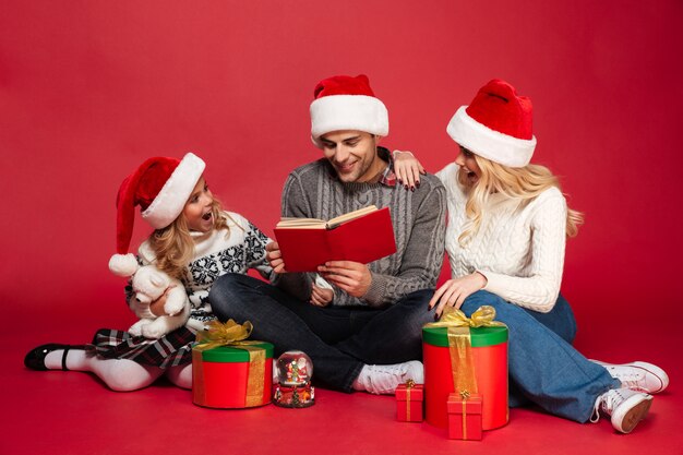 Familia joven con sombreros de Navidad sentado aislado