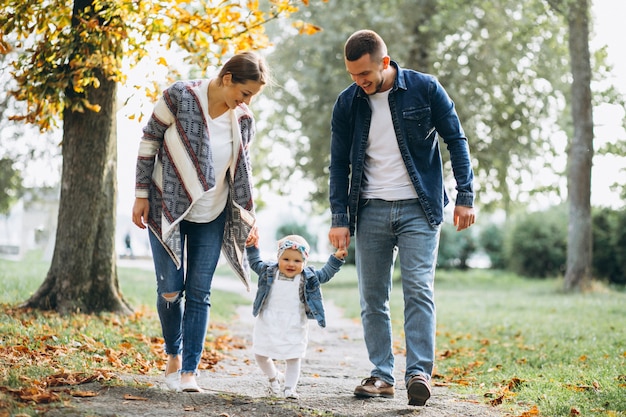 Familia joven con su pequeña hija en el parque otoño