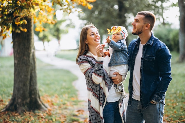 Familia joven con su pequeña hija en el parque otoño