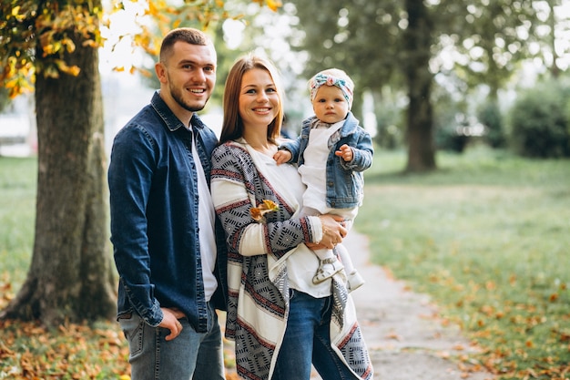 Familia joven con su pequeña hija en el parque otoño