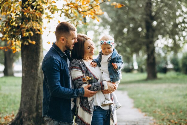 Familia joven con su pequeña hija en el parque otoño