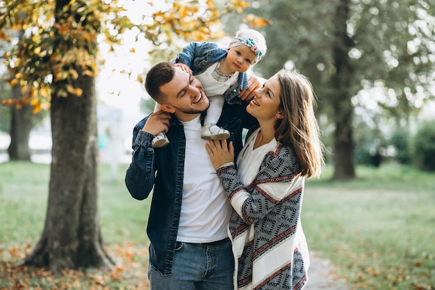 Familia joven con su pequeña hija en el parque otoño