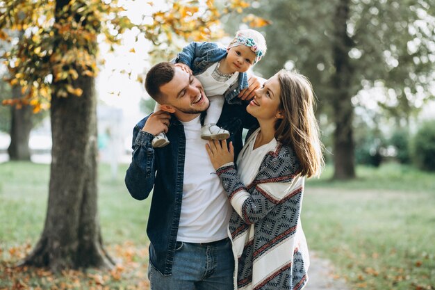 Familia joven con su pequeña hija en el parque otoño