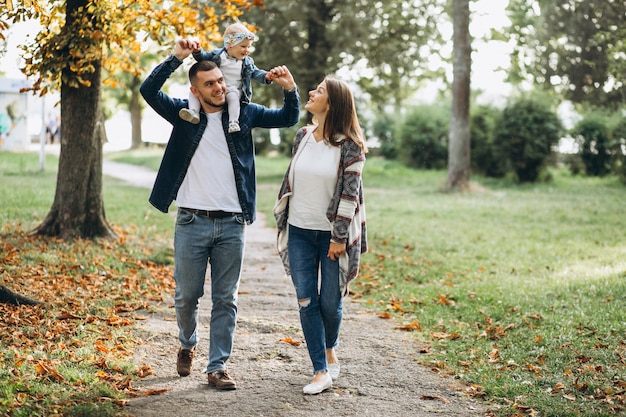 Familia joven con su pequeña hija en el parque otoño