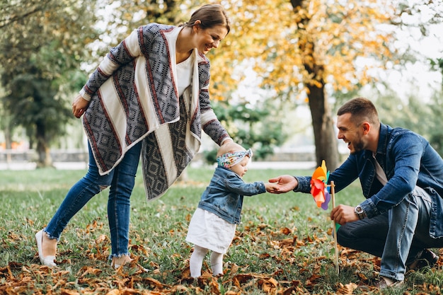 Familia joven con su pequeña hija en el parque otoño