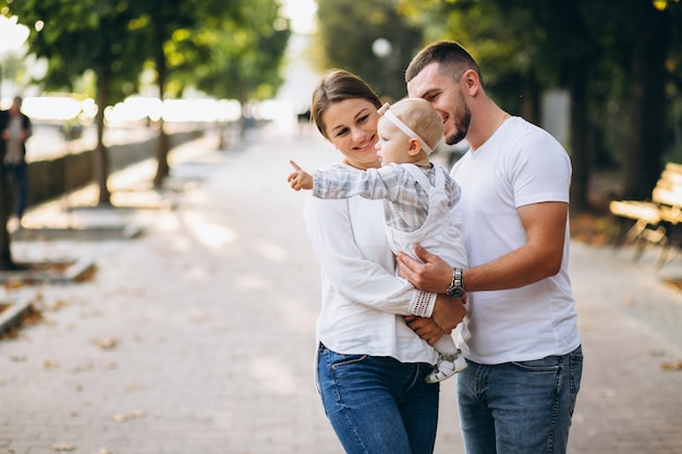 Familia joven con su pequeña hija en el parque otoño