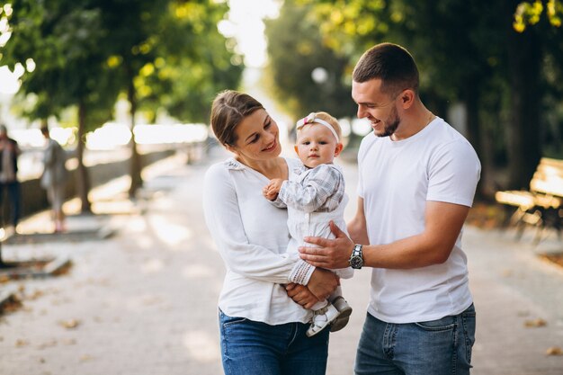 Familia joven con su pequeña hija en el parque otoño